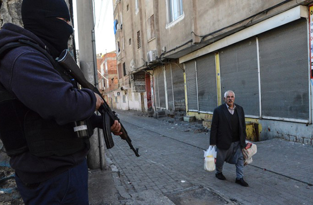 An elderly man walks past an armed government soldier during clashes in central Diyarbakir on March 17, 2016. Turkish security forces clashed with rebels in the main city of the Kurdish-dominated southeast on March 15, days after a deadly bombing in Ankara claimed by the Kurdistan Freedom Falcons (TAK), a radical Kurdish group with ties to the outlawed Kurdistan Workers' Party. / AFP / ILYAS AKENGIN        (Photo credit should read ILYAS AKENGIN/AFP/Getty Images)