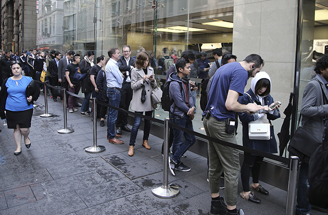 Customers line up out in the rain to purchase the new iPhone 7 or 7 Plus at the Apple store in Sydney, Australia, Friday, Sept. 16, 2016. The latest iPhone was released in the country on Friday. (AP Photo/Rob Griffith)